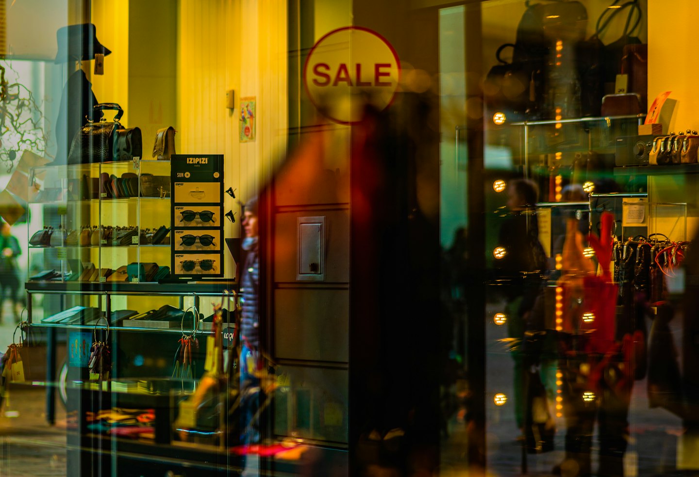 Display shelves in a shop window holding handbags and sunglasses.